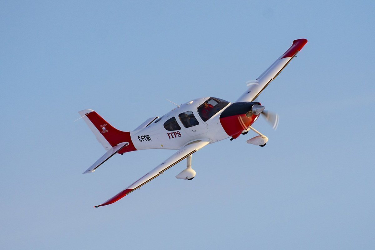 Red and white Cirrus-22 fixed wing plane in sky