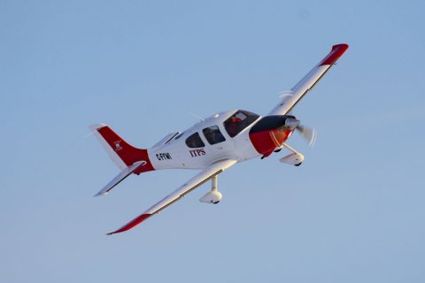 Red and white Cirrus-22 fixed wing plane in sky