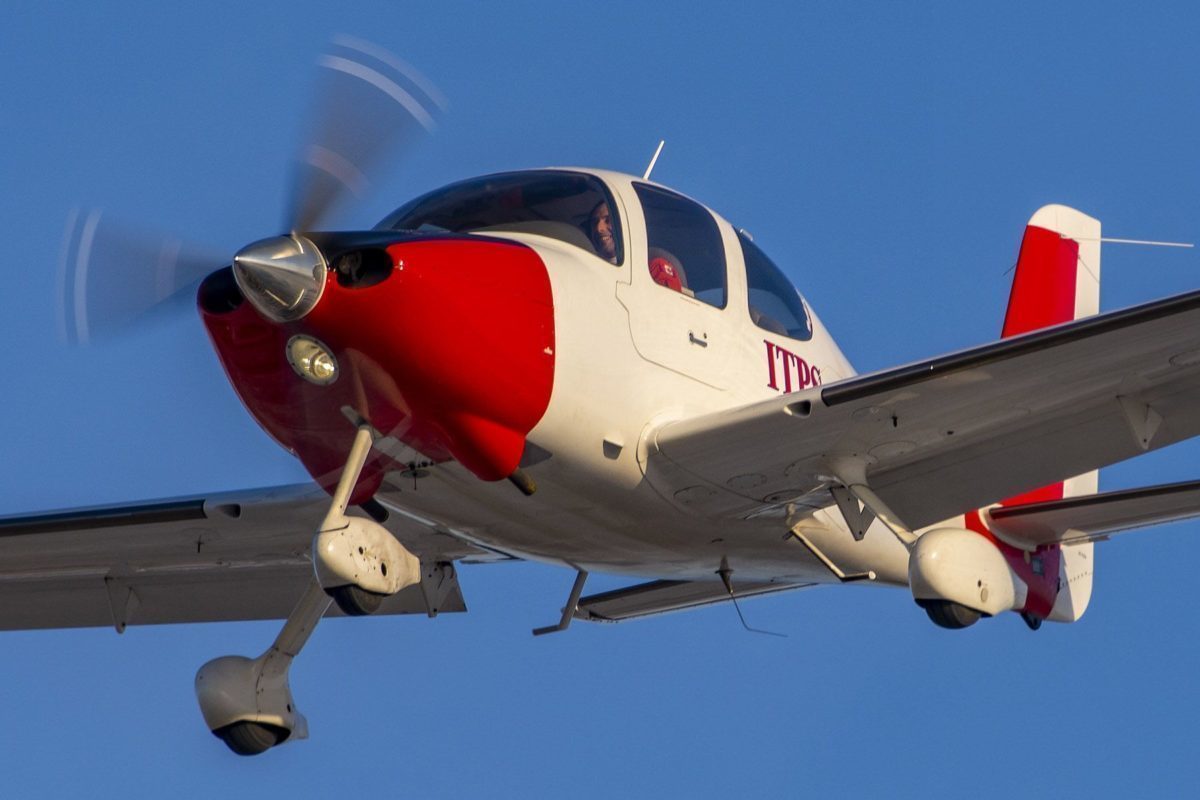 Red and white Cirrus SR22 fixed wing aircraft.
