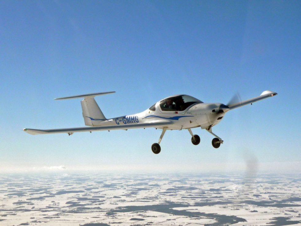 A white DA20-01 aircraft flying in the sky.