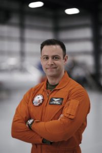 Dr. Panos Vitsas in orange flight suit in hangar.