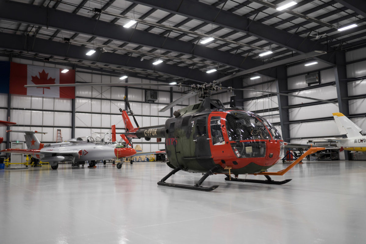 Green and red Bo-105M helicopter in hangar