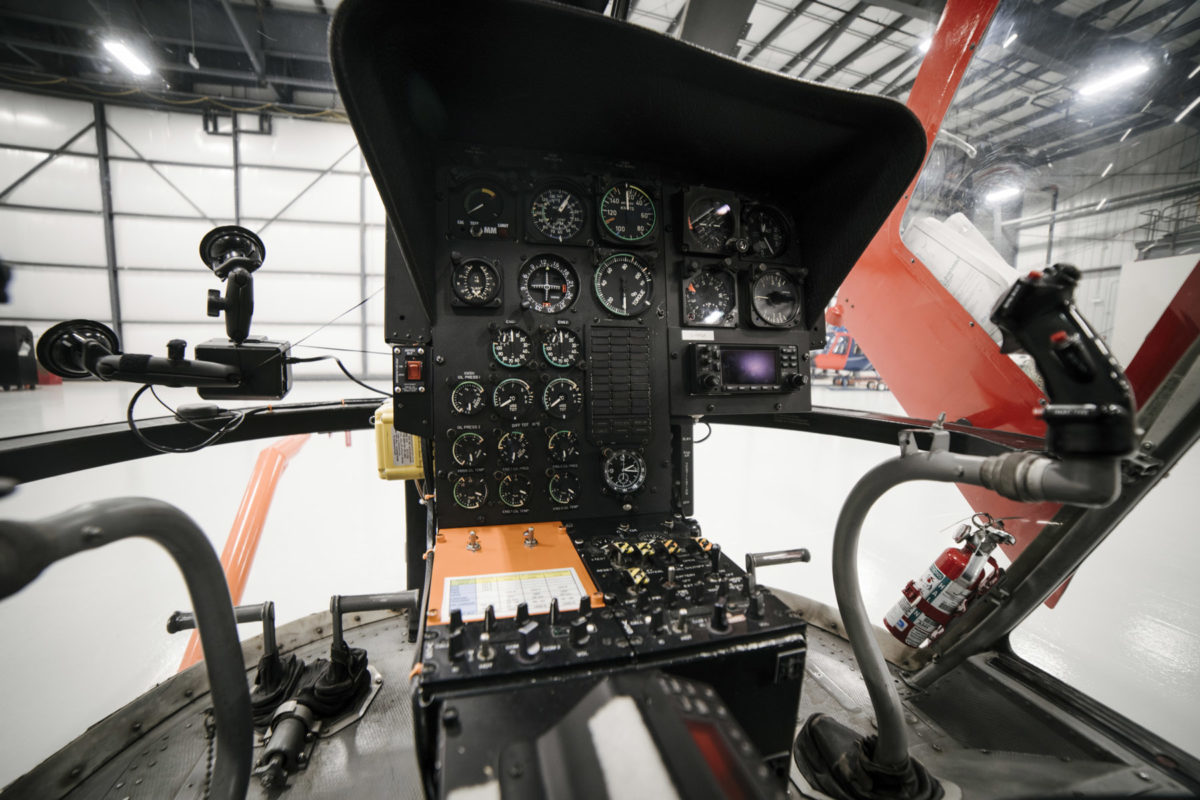 An aircraft cockpit showing many large and small gauges, as well as control knobs, on a black interface.