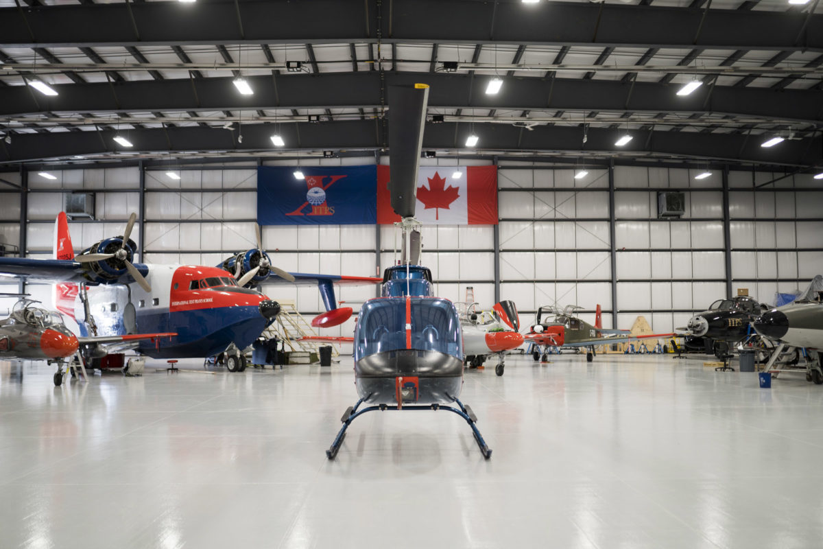 Blue and red Bell B106 helicopter with other aircraft in the ITPS hangar.
