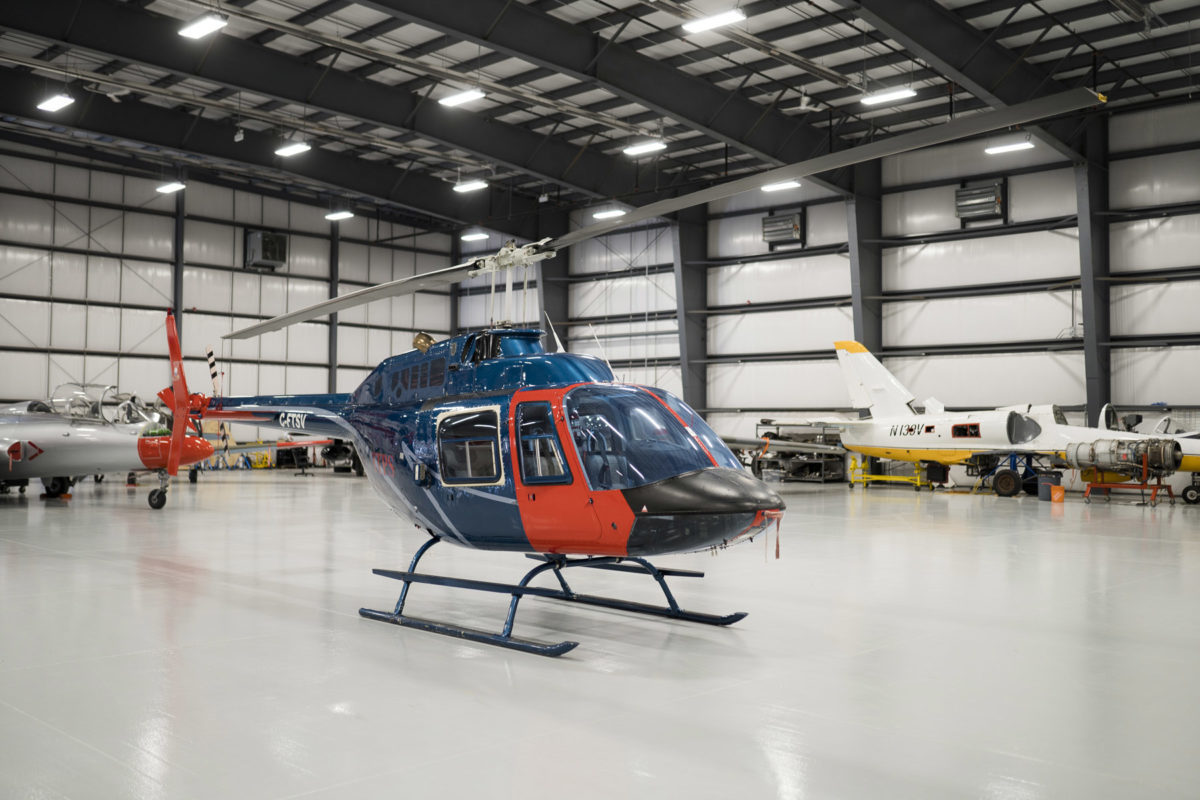 Blue and red Bell B106 helicopter in hangar.