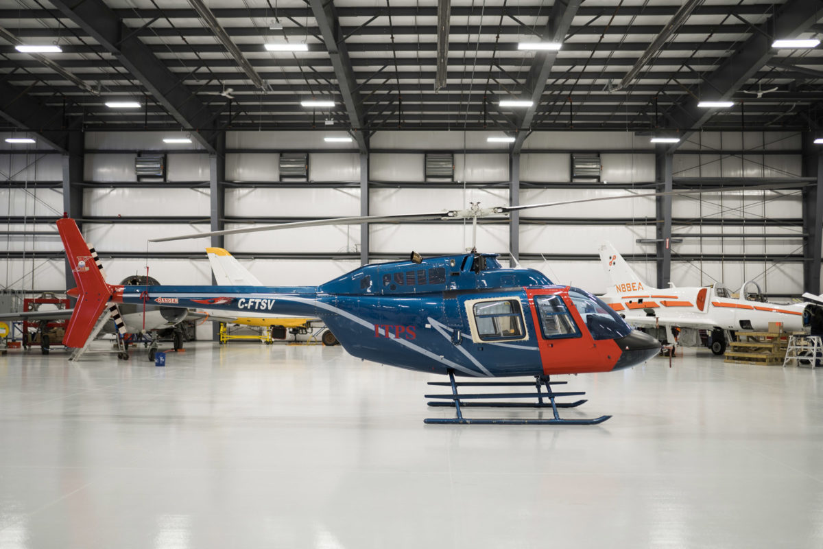 Blue and red Bell B106 helicopter in hangar