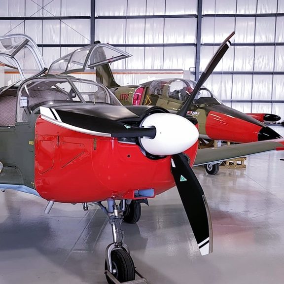 Close up of red and black IAR 832 Barsov next to a L-39. Both in hanger.