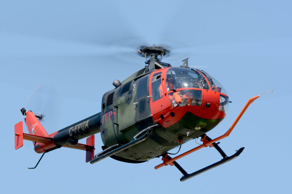 Green and red MBB Bo105 helicopter above