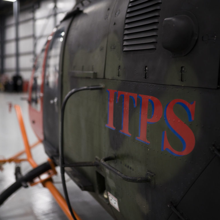 close up of an army green ITPS Aircraft Bo-106 side panels from the parked plane in the hangar.