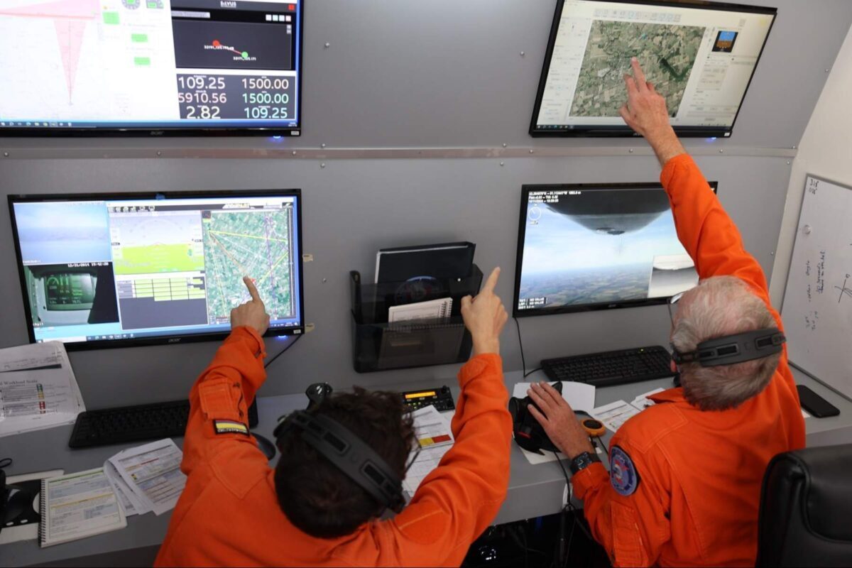 two test pilot instructors point at screens in ground control station