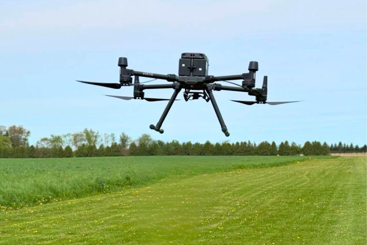 hovering black drone in grass field