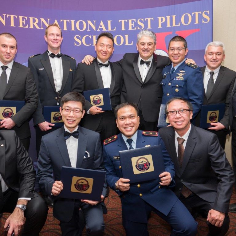 Test pilot graduates at ITPS Annual Flight Test Seminar. Men in military dress and business suits.
