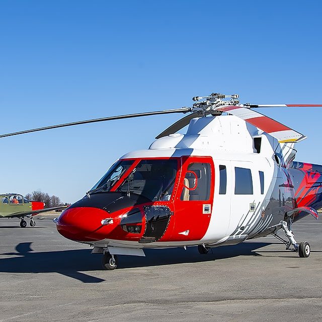 S76 Sikorsky red, white and blue helicopter sitting on the tarmac at International Test Pilots School