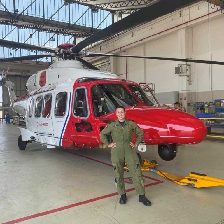 student standing in front of Leonardo red and white helicopter
