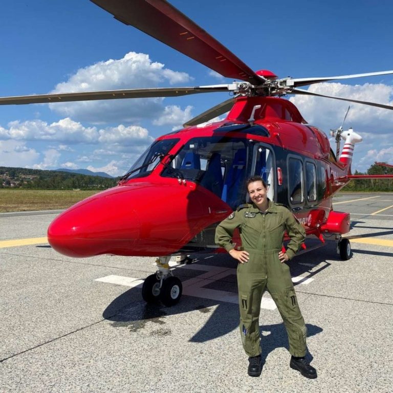 student in front of red helicopter on sunny day