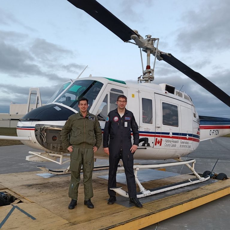 flight test students stand in front of white rotary wing aircraft