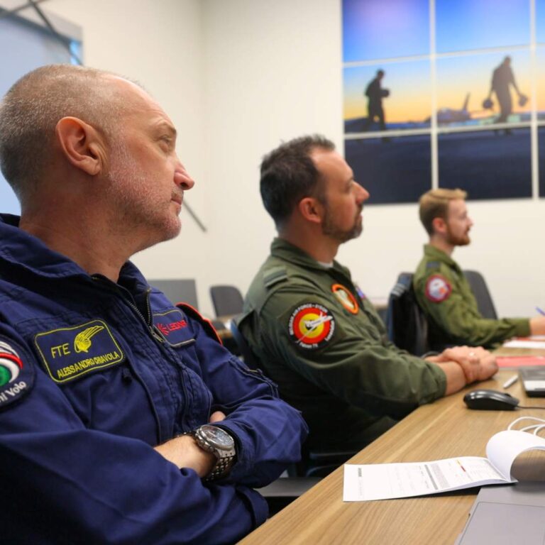 three students at desk attentively listening