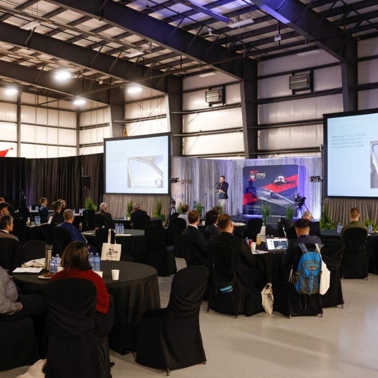 crowd of seated attendees facing speaker on stage