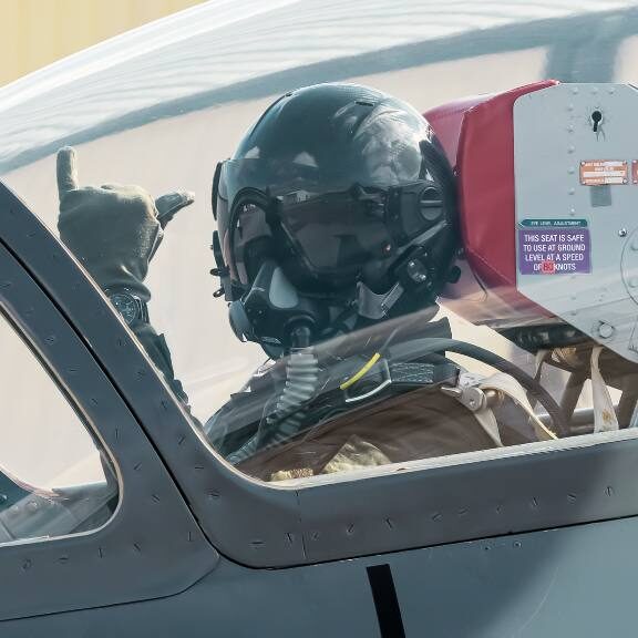 fighter pilot signaling to camera from cockpit
