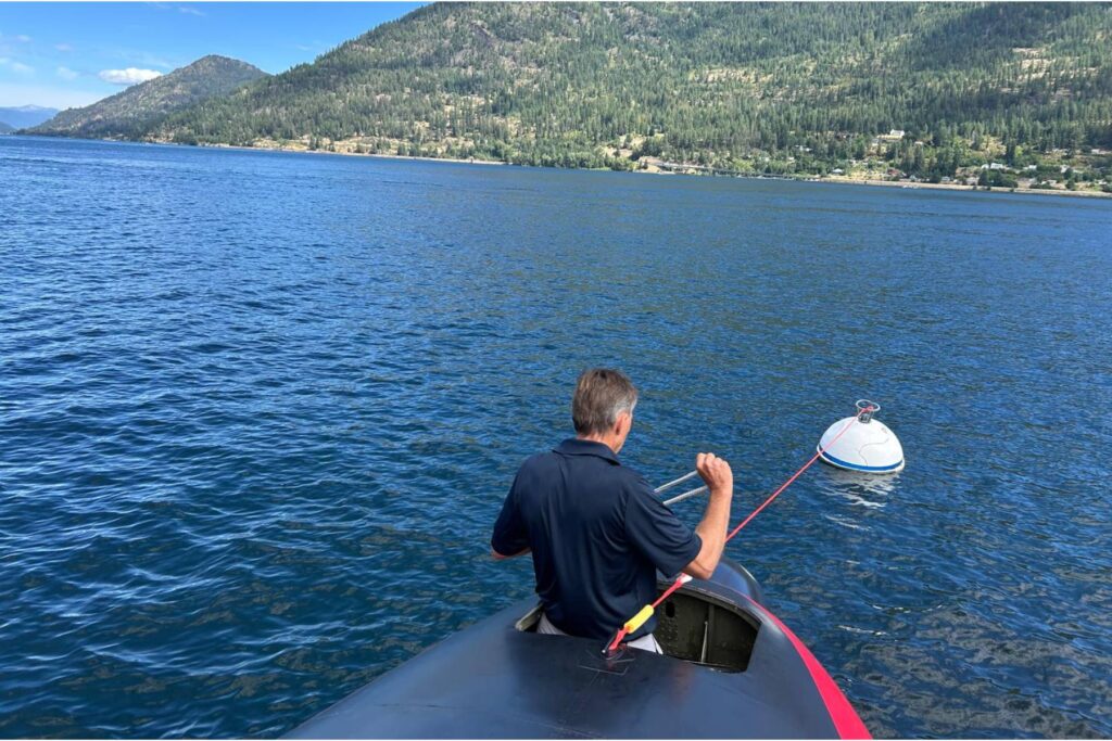 13 man tying rope to buoy on water from HU-16 nose