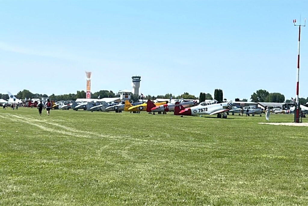 3 planes lined up for display on grass at airport