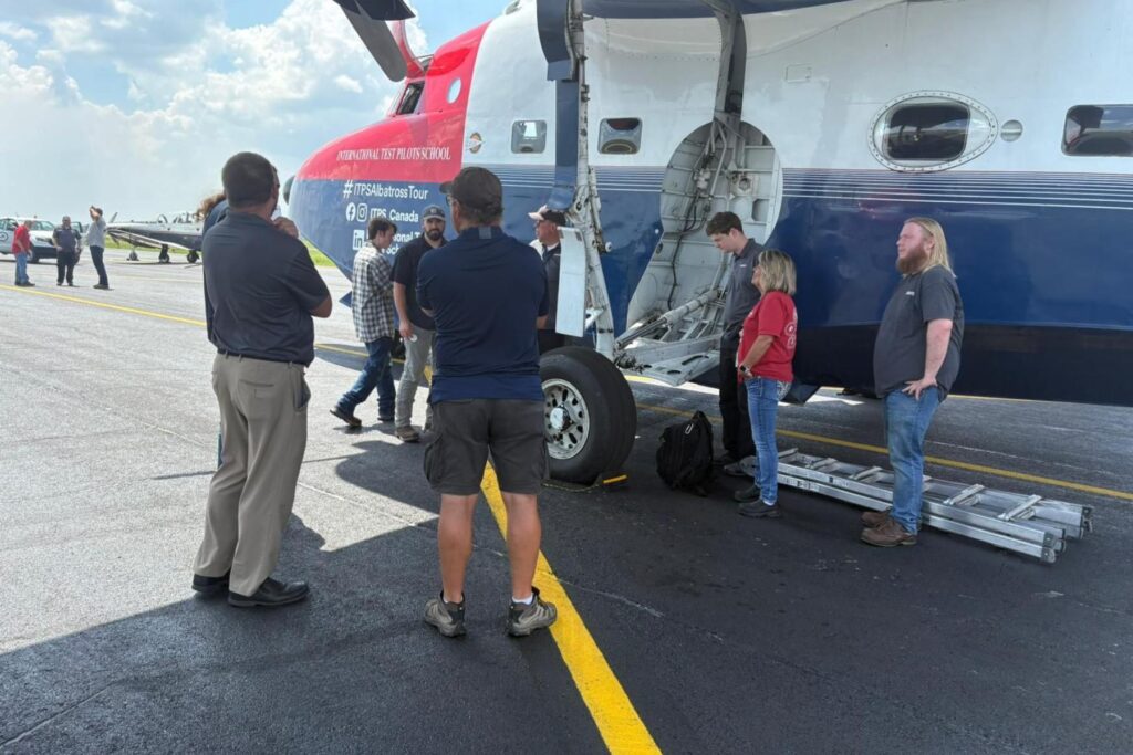 7 spectators stand beside HU-16 at Airbus