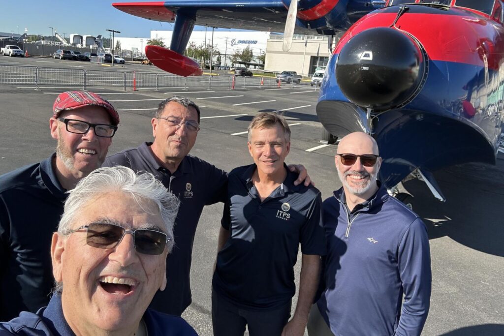 8 ITPS group stand together in front of Grumman HU-16 Albatross