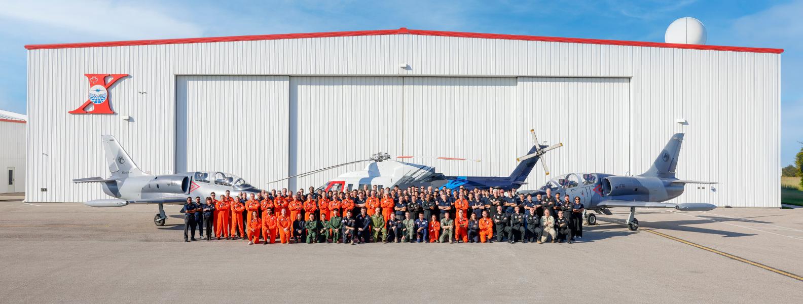 Untitled design ITPS Class Photo Staff and Students 2025 standing in front of hangar and aircraft