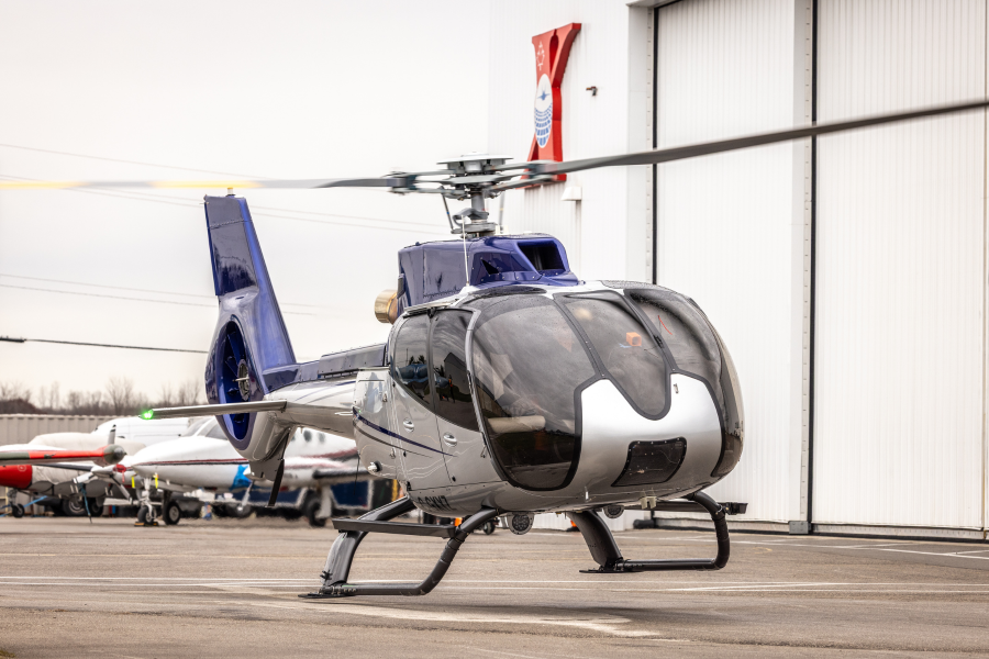 1 Airbus EC130T2 hovering above ground in front of ITPS hangar