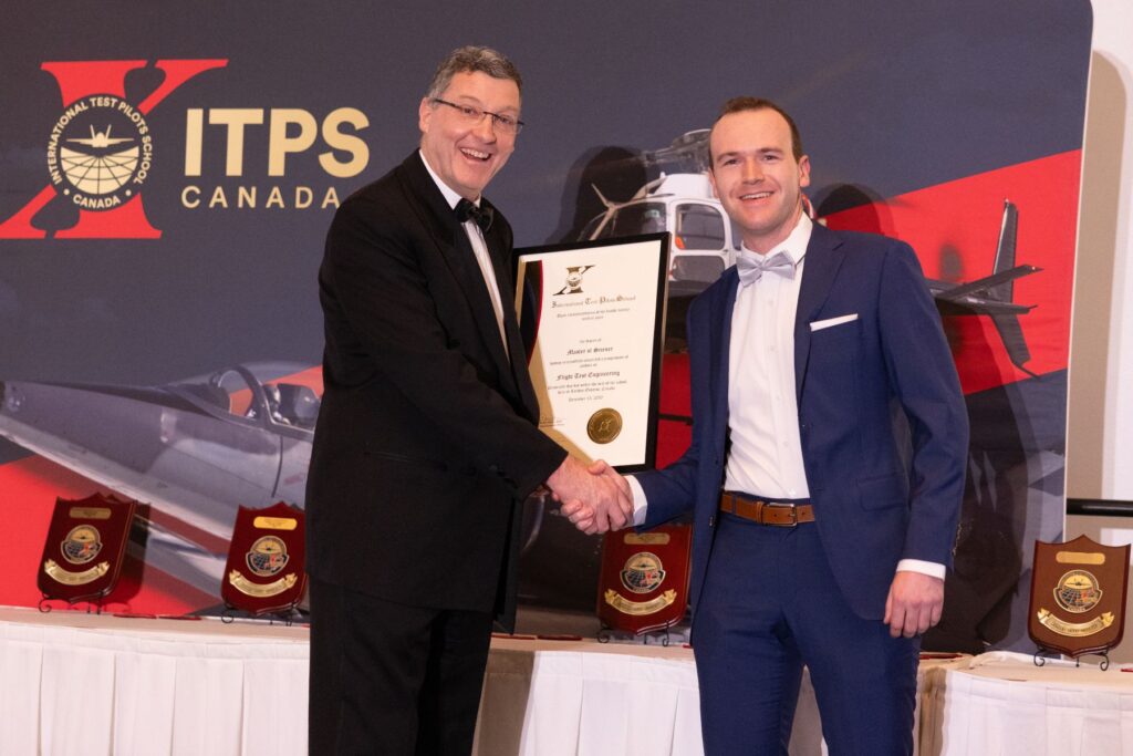 David 'Dos' Ostler holding plaque with graduating student