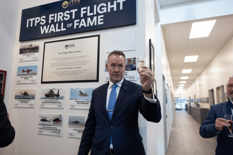7 Dave Lohse in front of ITPS wall of fame holding up glass of champagne for toast with wall of fame reveal