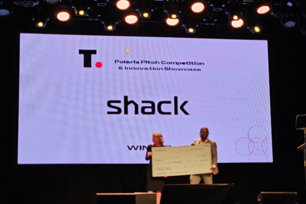 2 Two people on stage holding large cheque at TechAlliance event