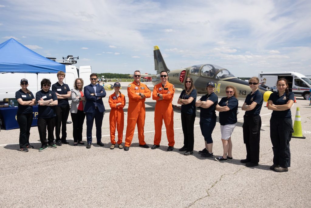 ITPS staff, instructors and volunteers stand together on runway in front of L39