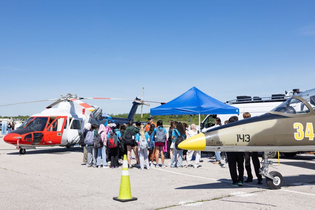 girls and young women gathered at ITPS booth between Helicopter and L39 jet