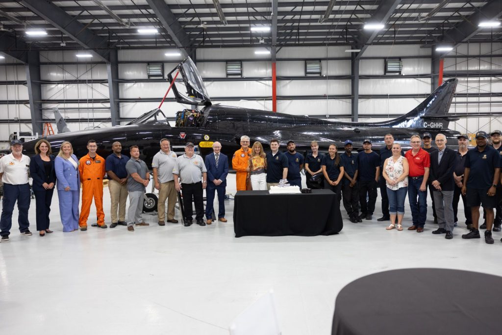 6 attendees and flight enthusiasts gather in front of hawker hunter in ITPS hangar