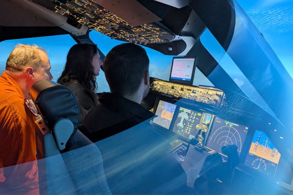 8 Honeywell Aerospace students in ITPS simulator cockpit